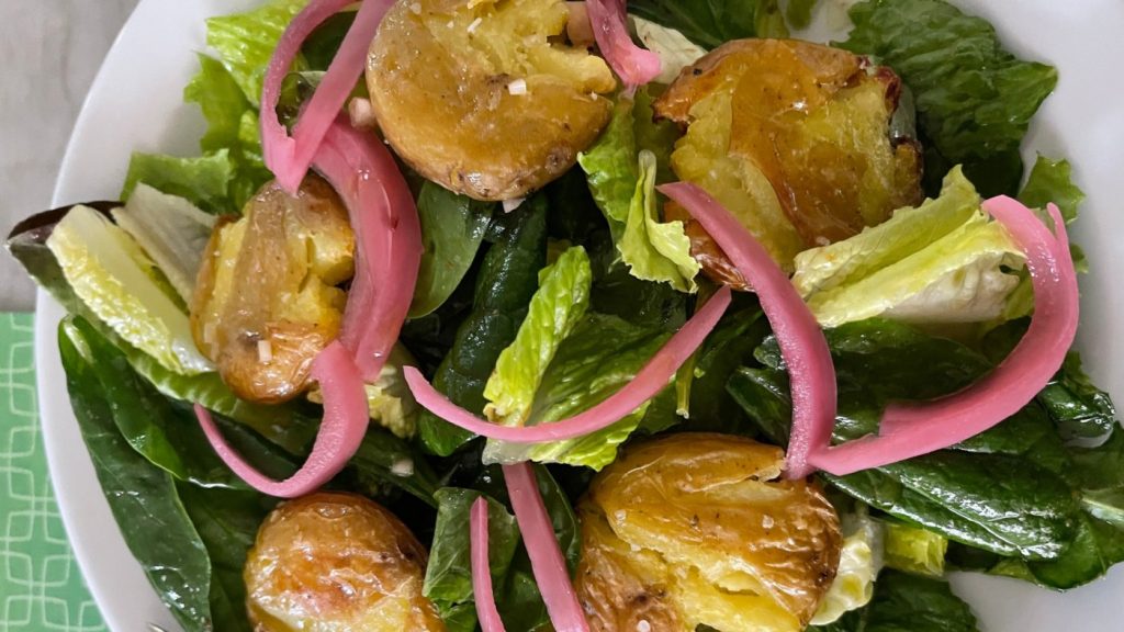 Recipe: This green salad is garnished with smashed potatoes warm from the oven