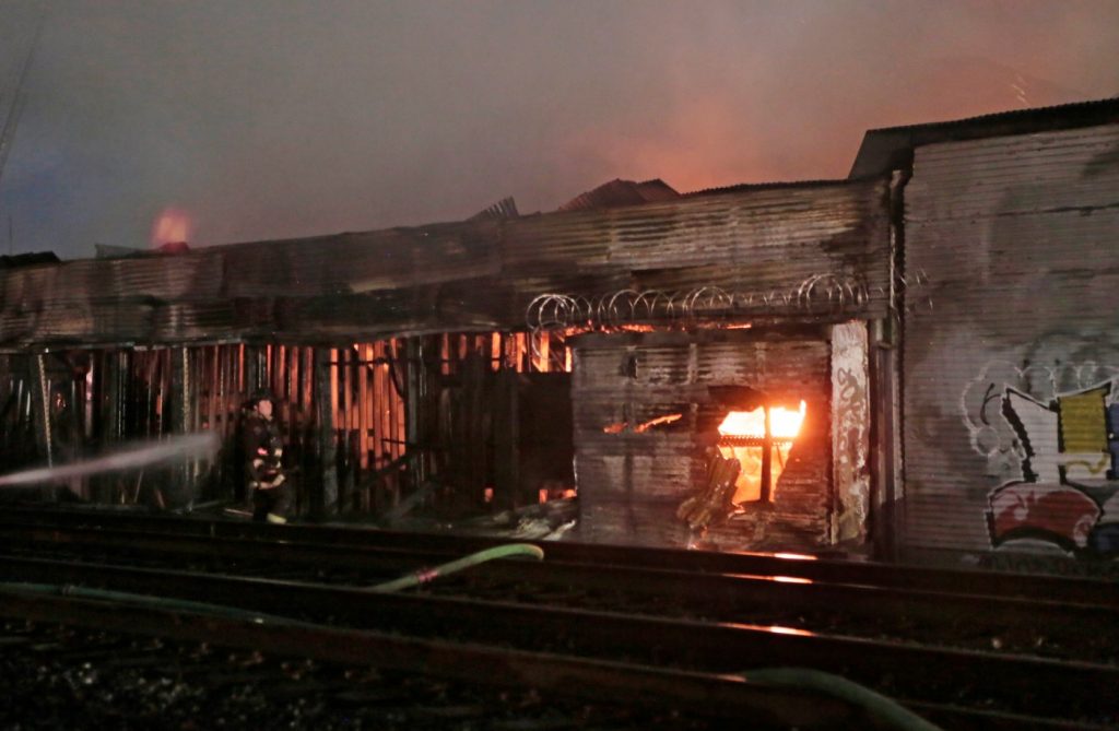 Huge Oakland lumber yard blaze smolders as firefighters probe cause